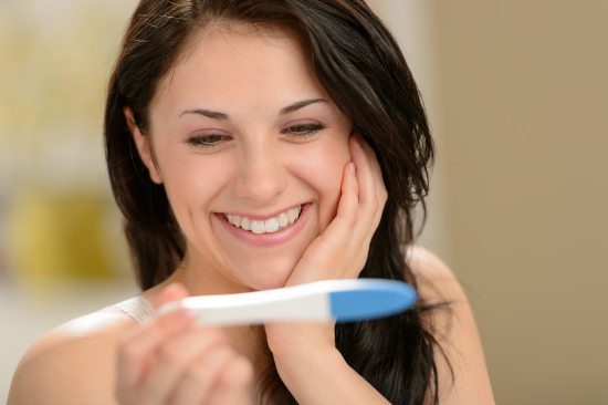 Счастливая девушка с тестом на беременность