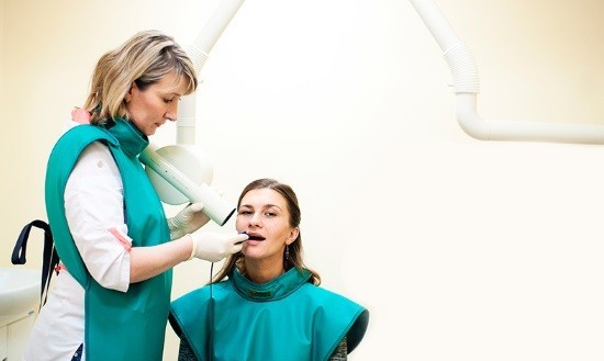 Женщине делают прицельный снимок зуба во время беременности