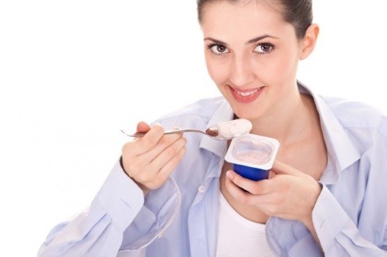Молодая женщина ест йогурт